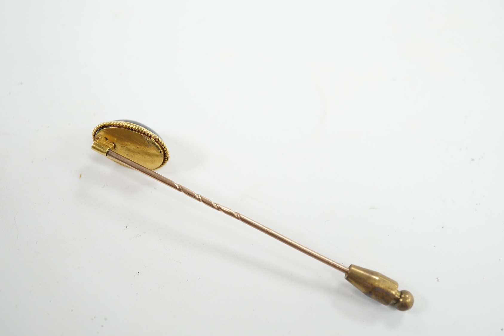 A cased Victorian yellow metal, oval cabochon garnet and diamond chip set stick pin, overall 77mm. Condition - fair